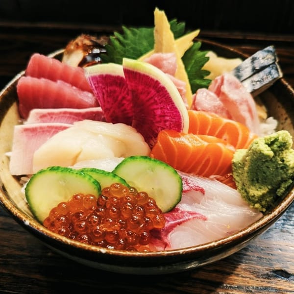 A colorful chirashi bowl from Ginya Izakaya, featuring various sashimi, roe, and vegetables.