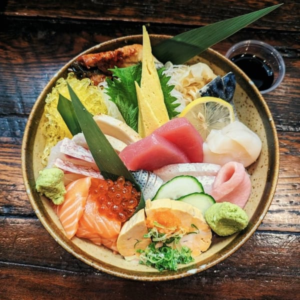 A colorful chirashi bowl from Ginya Izakaya, featuring various fresh sashimi, roe, and garnishes.